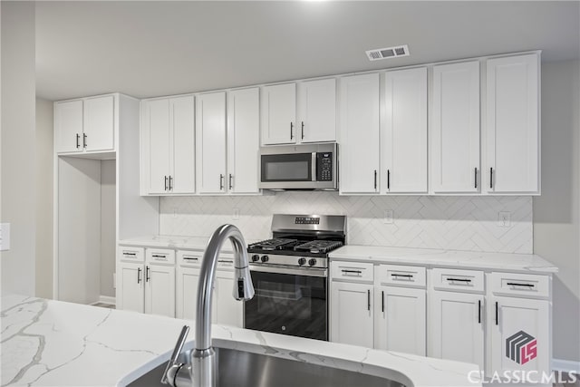 kitchen with light stone counters, white cabinetry, appliances with stainless steel finishes, and tasteful backsplash