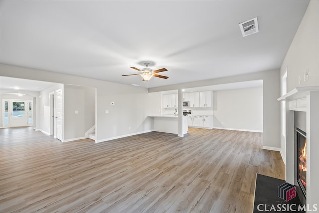 unfurnished living room featuring light wood-type flooring and ceiling fan