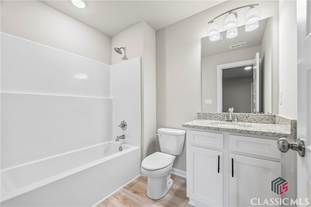 full bathroom with hardwood / wood-style flooring, vanity, shower / bathtub combination, and toilet