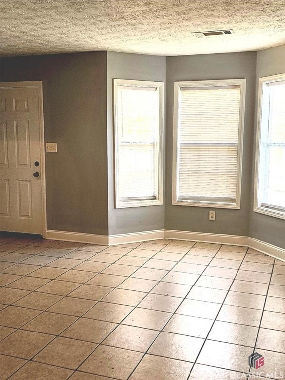 entryway with light tile patterned floors and a textured ceiling