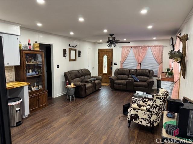 living room featuring ceiling fan and dark hardwood / wood-style flooring