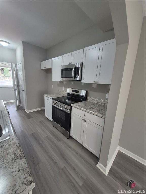 kitchen featuring white cabinetry, light stone counters, dark hardwood / wood-style floors, and appliances with stainless steel finishes