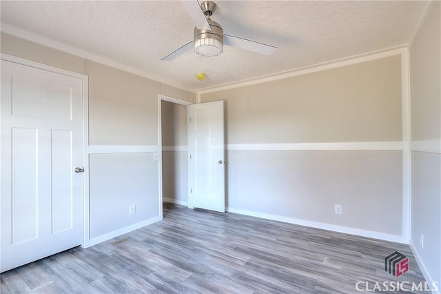 spare room featuring ceiling fan, crown molding, wood-type flooring, and a textured ceiling