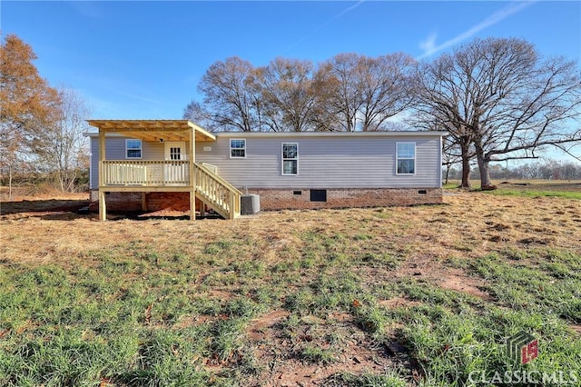 back of property featuring a lawn, a deck, and central AC