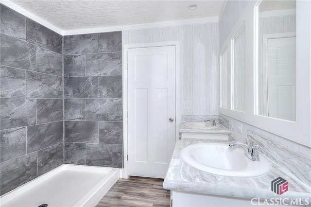 bathroom with a shower, wood-type flooring, a textured ceiling, vanity, and ornamental molding