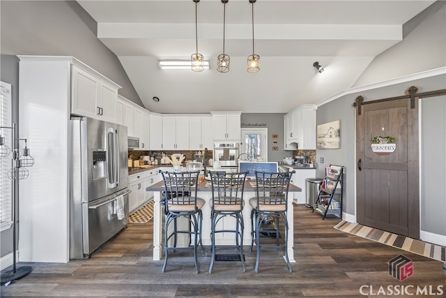 kitchen with decorative backsplash, appliances with stainless steel finishes, pendant lighting, a barn door, and white cabinets