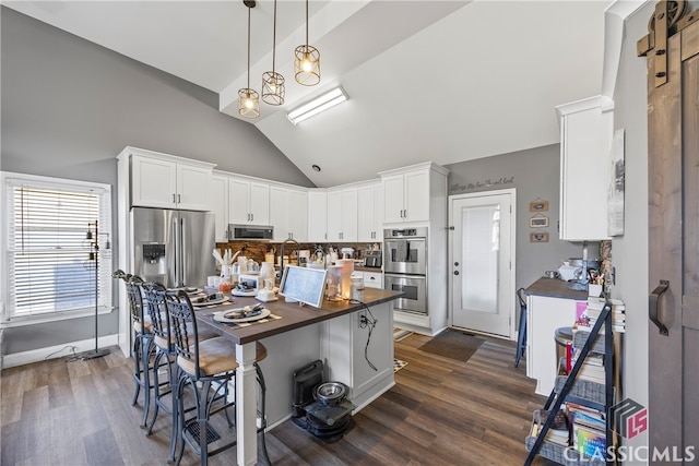 kitchen with white cabinets, a kitchen breakfast bar, stainless steel appliances, and butcher block counters