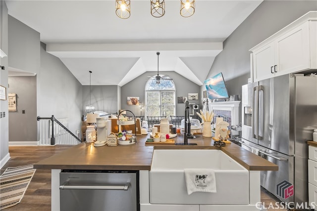 kitchen with white cabinets, lofted ceiling, butcher block counters, and stainless steel appliances