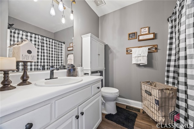 bathroom with toilet, vanity, and hardwood / wood-style flooring