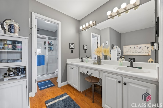 bathroom featuring hardwood / wood-style floors, vanity, a shower with shower door, and toilet