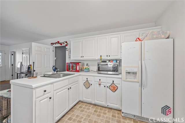 kitchen featuring white cabinetry, sink, white fridge with ice dispenser, and kitchen peninsula