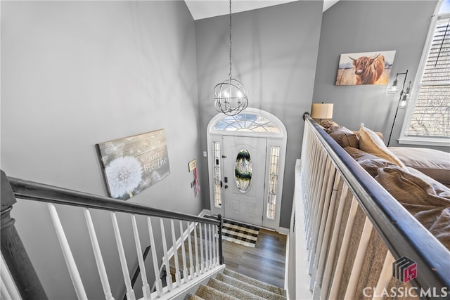 foyer featuring a towering ceiling, hardwood / wood-style flooring, and a notable chandelier