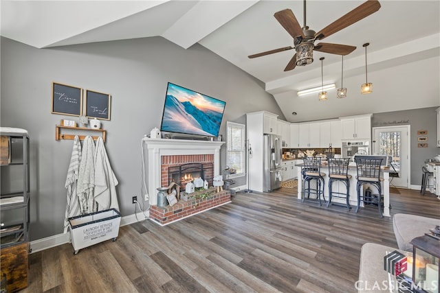 living room with a fireplace, vaulted ceiling, ceiling fan, and dark wood-type flooring