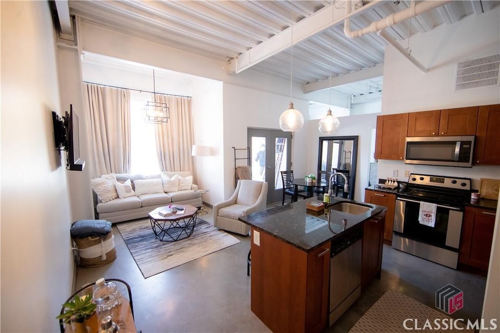 kitchen with a kitchen island with sink, hanging light fixtures, stainless steel appliances, and french doors