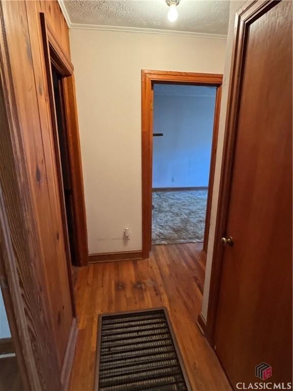 hall featuring hardwood / wood-style floors, a textured ceiling, and crown molding