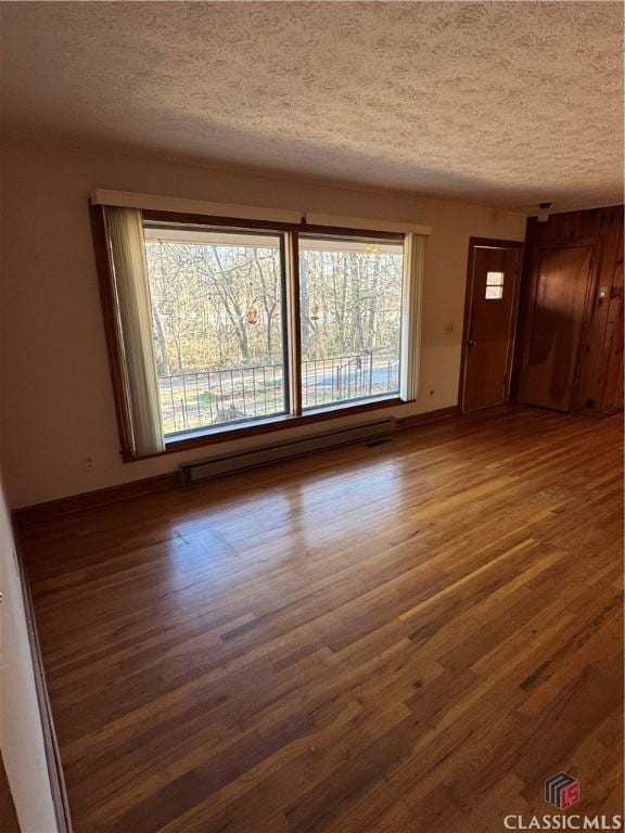 unfurnished living room with dark wood-type flooring, a textured ceiling, and a baseboard radiator