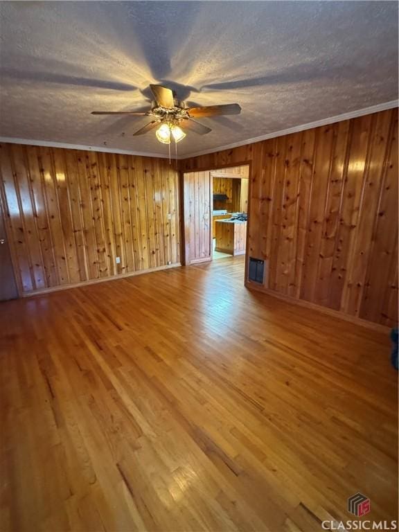 spare room with wooden walls, hardwood / wood-style floors, and a textured ceiling