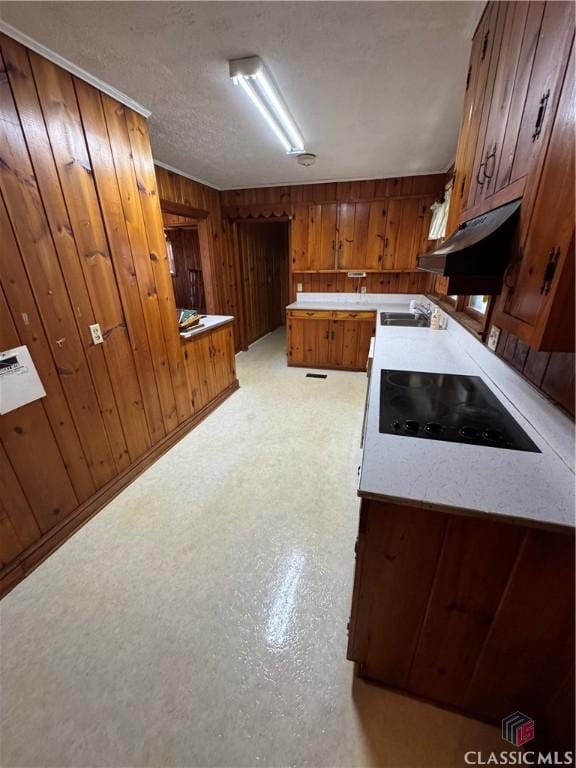 kitchen with black electric cooktop, wooden walls, sink, and a textured ceiling