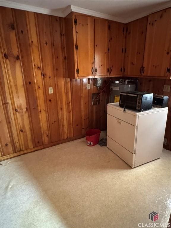 clothes washing area with wood walls, water heater, cabinets, and washer / dryer