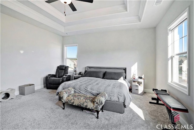 carpeted bedroom with multiple windows, a raised ceiling, and ceiling fan