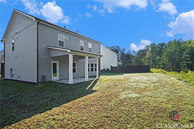 back of property with a lawn and a patio