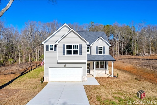 front of property featuring covered porch, a garage, and a front yard