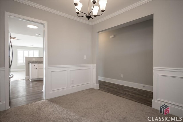 unfurnished room with dark colored carpet, ceiling fan with notable chandelier, and crown molding