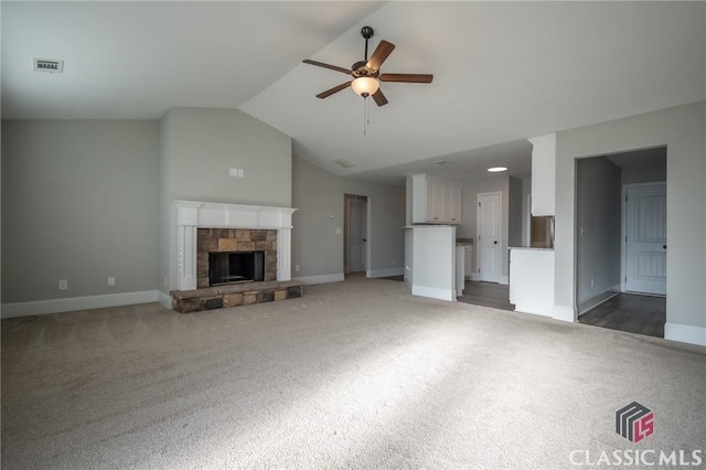 unfurnished living room with ceiling fan, a fireplace, lofted ceiling, and dark colored carpet