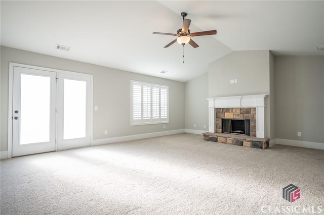 unfurnished living room with ceiling fan, a healthy amount of sunlight, a stone fireplace, and light carpet