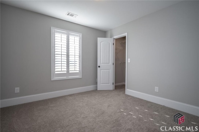 unfurnished bedroom with a spacious closet and carpet floors