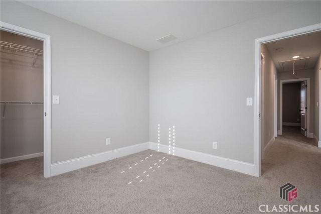 unfurnished bedroom with light colored carpet, a spacious closet, and a closet