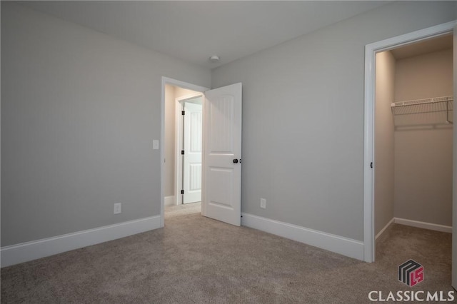 unfurnished bedroom featuring light colored carpet, a spacious closet, and a closet