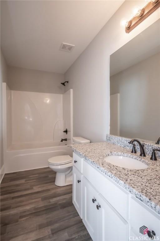 full bathroom featuring vanity,  shower combination, toilet, and wood-type flooring