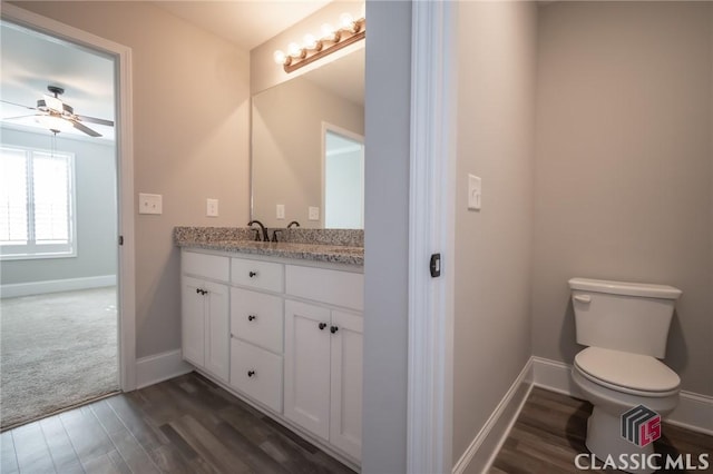 bathroom featuring ceiling fan, toilet, wood-type flooring, and vanity