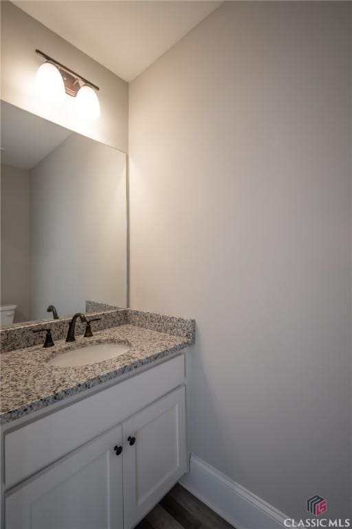 bathroom with hardwood / wood-style floors, vanity, and toilet