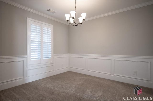 carpeted empty room featuring a chandelier and ornamental molding