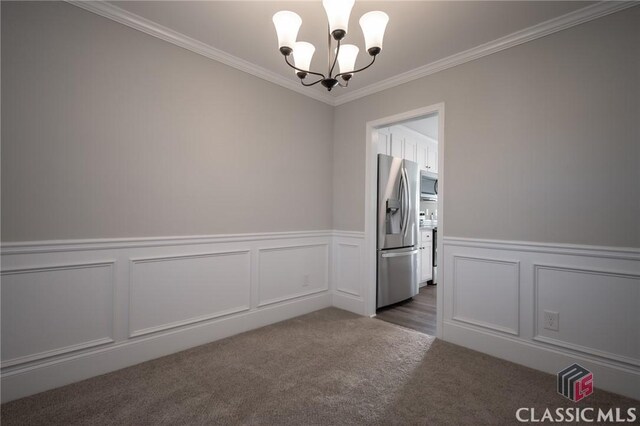 carpeted empty room featuring an inviting chandelier and ornamental molding