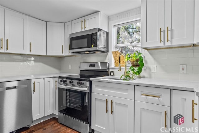 kitchen featuring tasteful backsplash, stainless steel appliances, sink, dark hardwood / wood-style floors, and white cabinetry