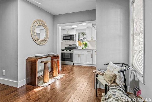 interior space with white cabinets, dark hardwood / wood-style floors, and appliances with stainless steel finishes