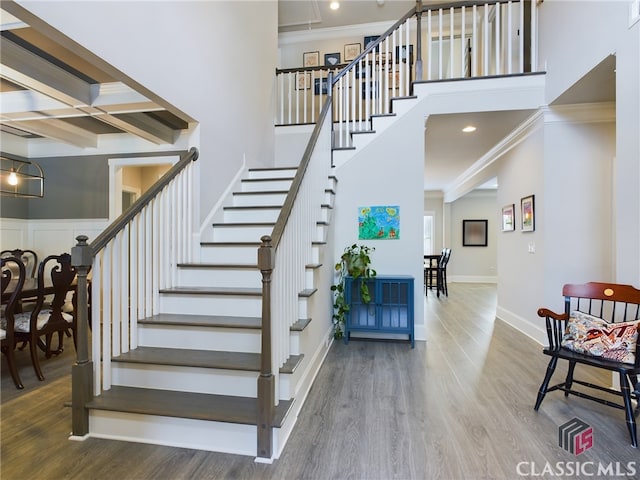 stairway with beam ceiling, crown molding, coffered ceiling, and hardwood / wood-style flooring