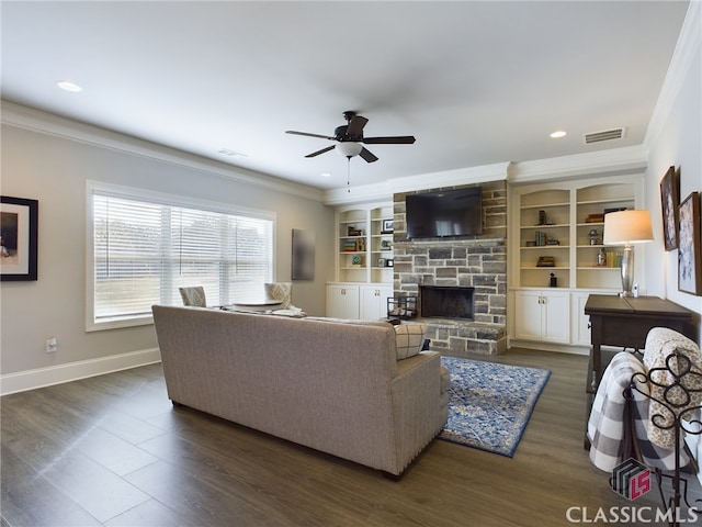 living room with ornamental molding, built in shelves, ceiling fan, dark wood-type flooring, and a fireplace