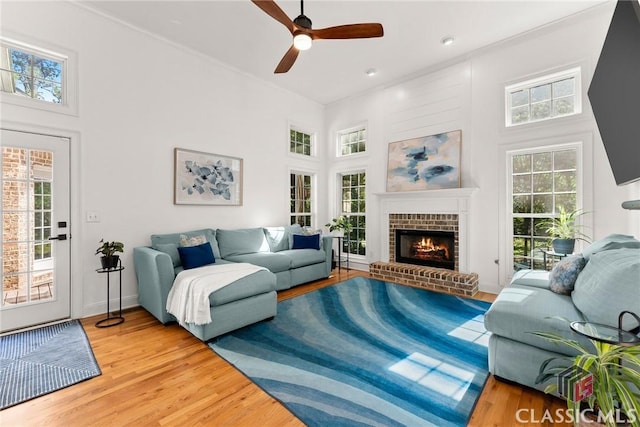 living room with a wealth of natural light, wood-type flooring, and a brick fireplace