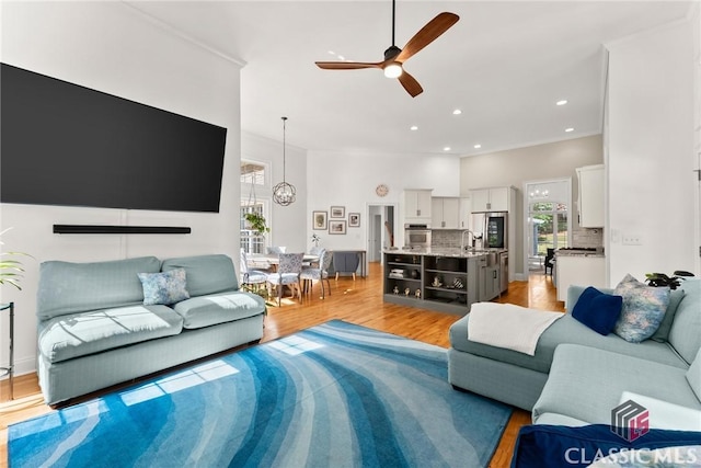 living room with light hardwood / wood-style floors, ceiling fan, ornamental molding, and sink