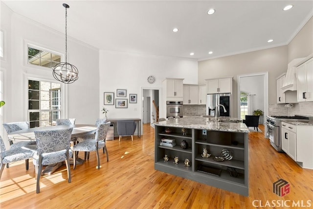 kitchen featuring white cabinets, an island with sink, appliances with stainless steel finishes, and tasteful backsplash