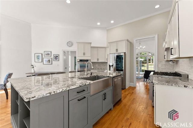 kitchen featuring tasteful backsplash, an inviting chandelier, an island with sink, and appliances with stainless steel finishes