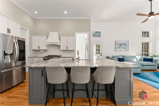 kitchen featuring a large island with sink, stainless steel fridge with ice dispenser, and white cabinets