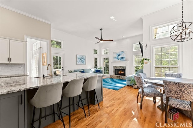 kitchen with light stone countertops, a fireplace, sink, white cabinets, and hanging light fixtures