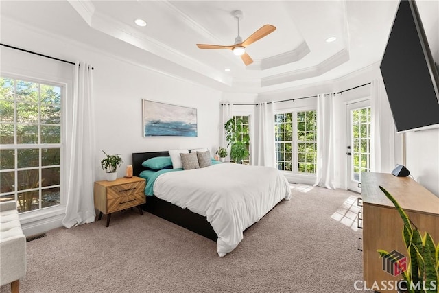 carpeted bedroom with a tray ceiling, ceiling fan, and ornamental molding