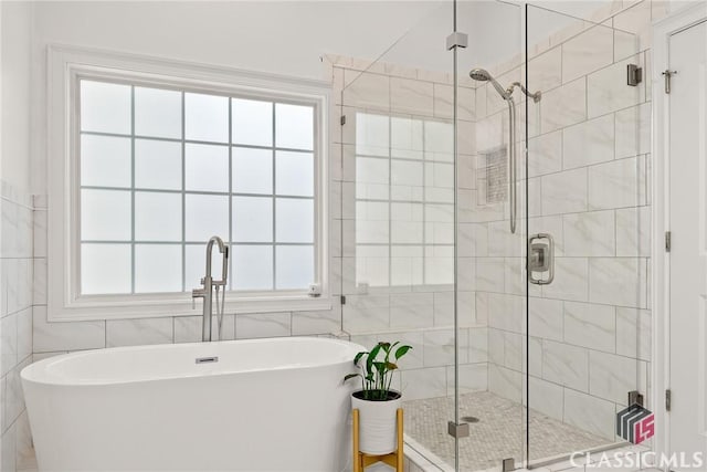 bathroom with tile walls and shower with separate bathtub