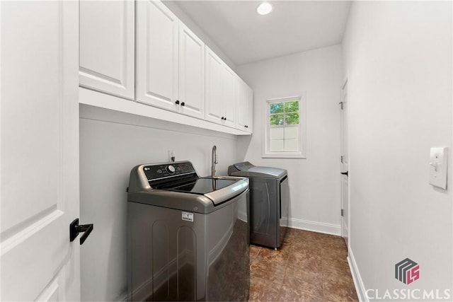 clothes washing area with cabinets and washer and dryer